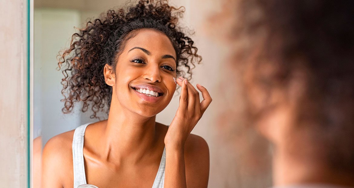 Jovem mulher negra cuida do rosto depois da depilação facial